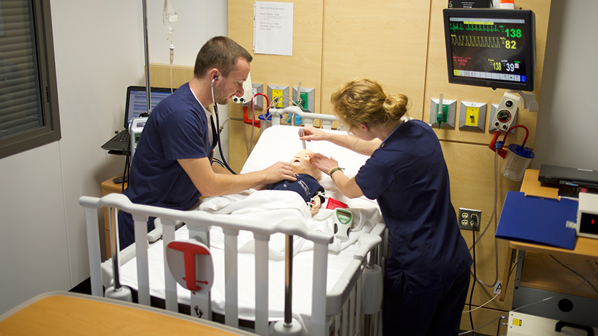 Two nursing students caring for a baby mannequin, part of the SimMom set in Cedarville University’s Health Sciences Simulation Center.