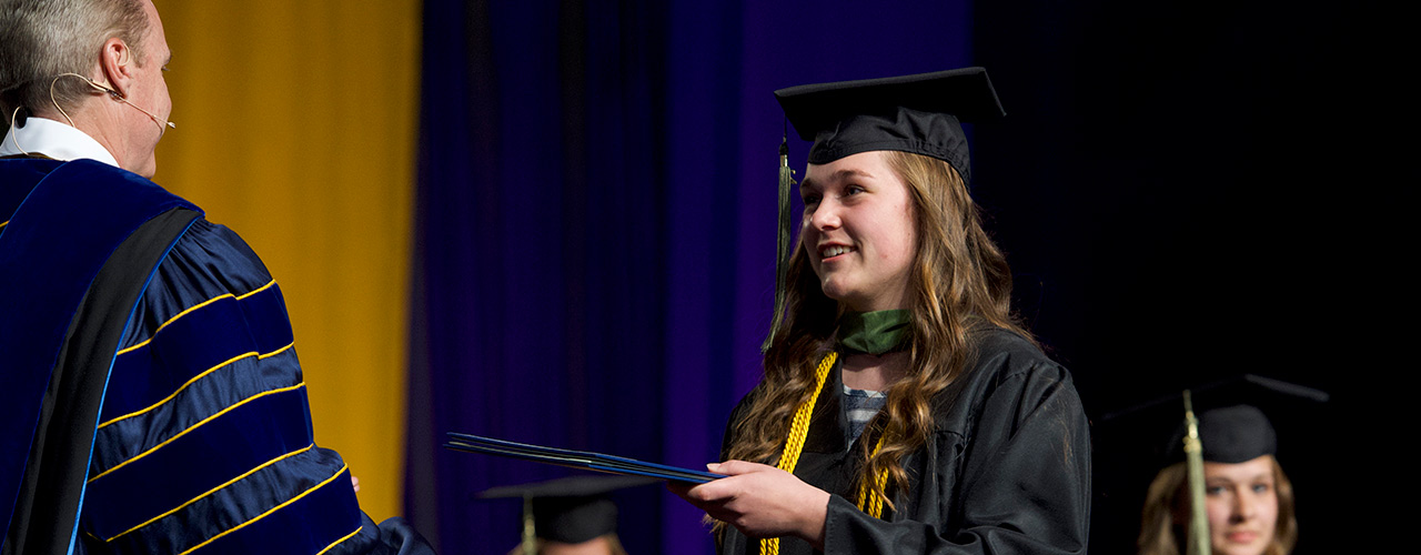 A student receives her diploma from Dr. Thomas White, president of Cedarville University