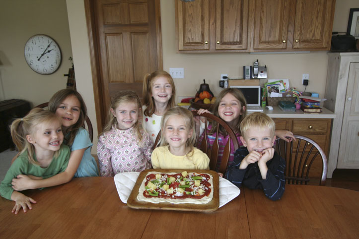 Sarah-Kate, Anna, and Simon make pineapple pizza with friends.