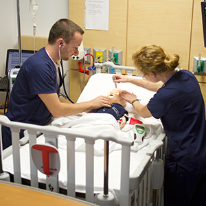 Two nursing students check the status of a child simulator