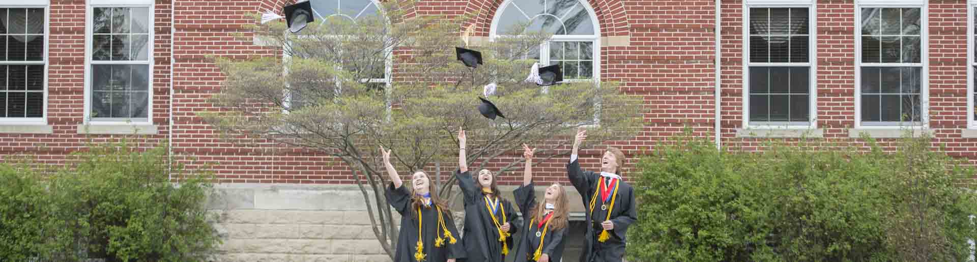 Oxford students throwing their caps while dressed in graduation regalia.