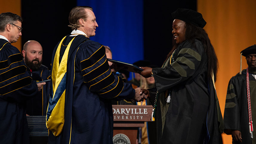 A student receives her diploma from President White.