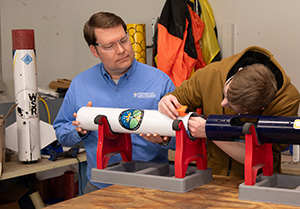 Dr. Joe Miller works with a student on a rocket for the NASA Student Launch.
