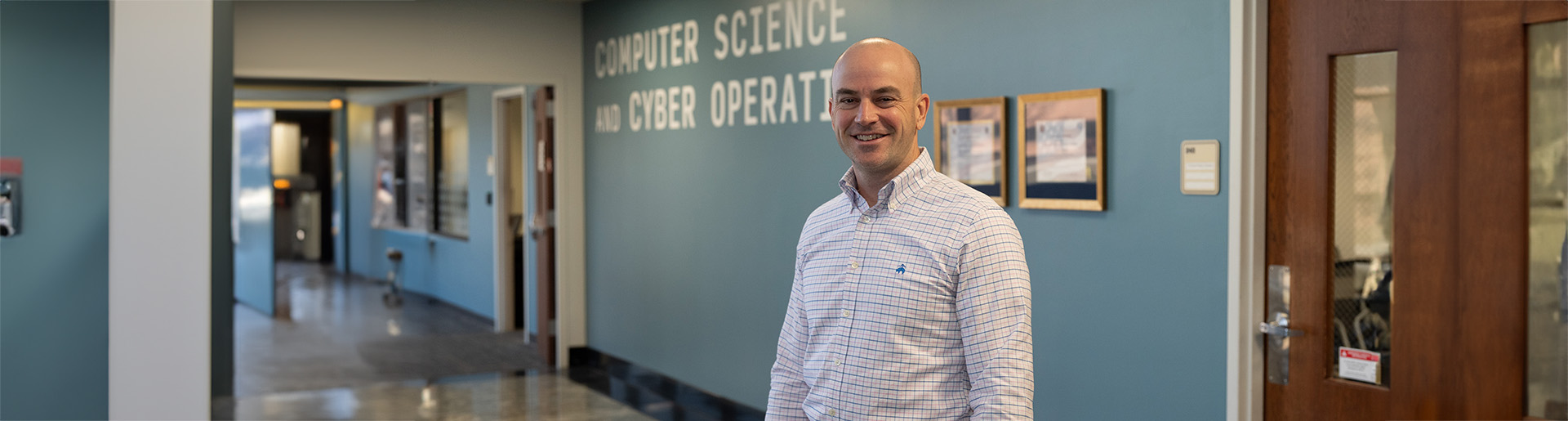Dr. Seth Hamman smiling in front of Cyber Operations classroom.