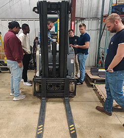 Cedarville University electrical engineering students work on a Crown fork truck.