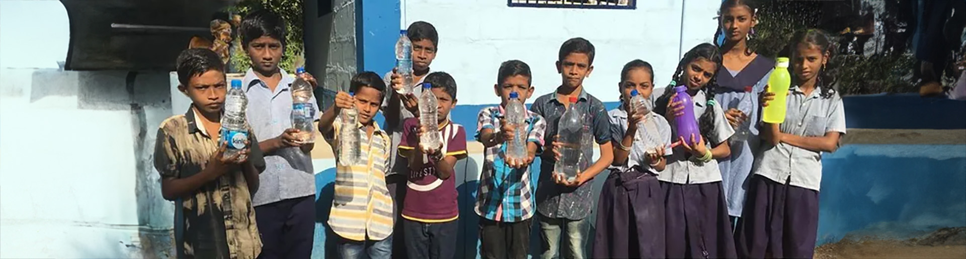 Children in India display their bottles of clean water thanks to Global Water Consortium.