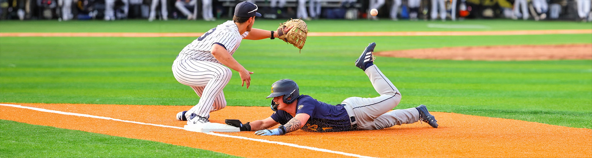 Baseball player sliding into third base.
