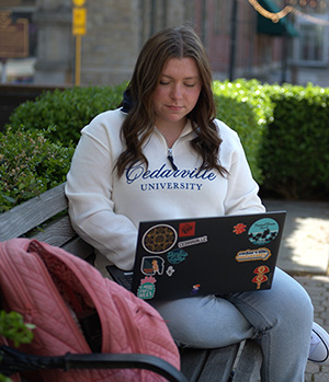 Abby Antram sitting on a bench working on a laptop.