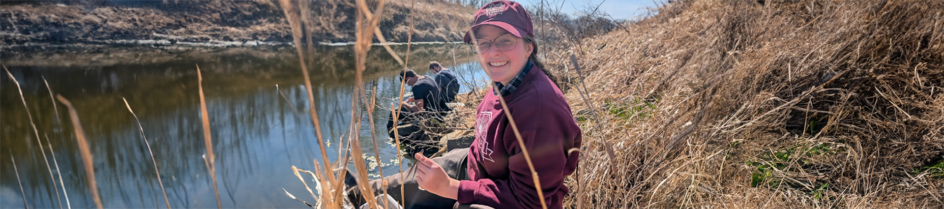 Abby Paulding sits beside a river collecting midges from the water.