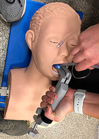 ARC trauma clamp with laryngoscope being used on a man mannequin.