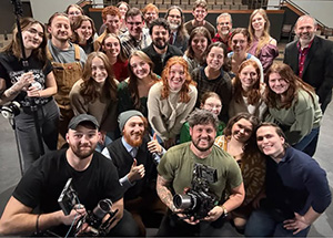 Large group of Cedarville University students with film crew holding cameras.