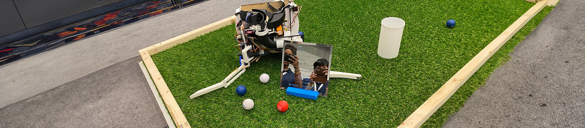 The Cedar Gleaner robot picking up golf balls on a green turf course.