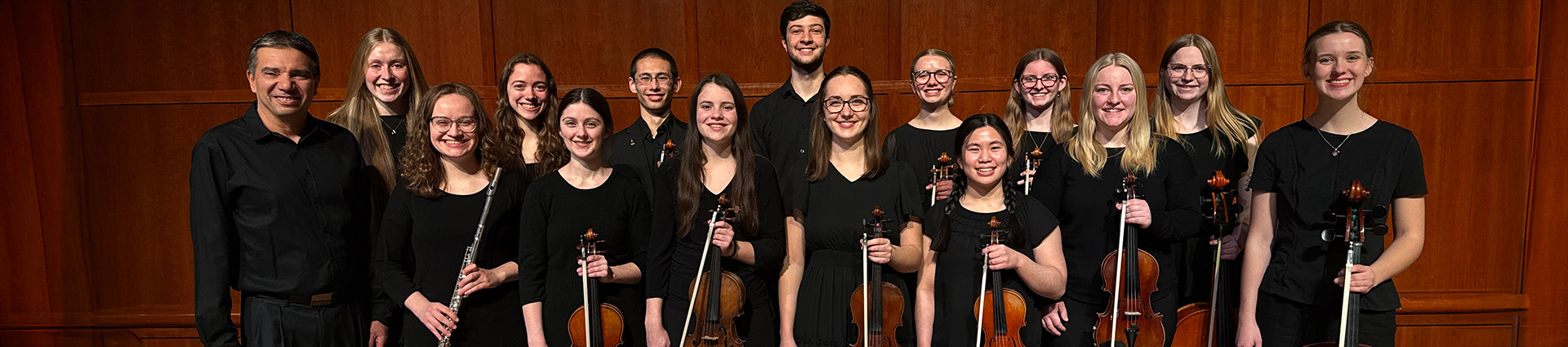 Chamber orchestra students pose for a photo with their instruments.
