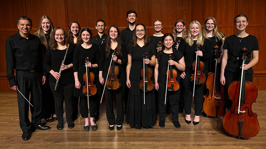 Chamber orchestra students pose for a photo with their instruments.