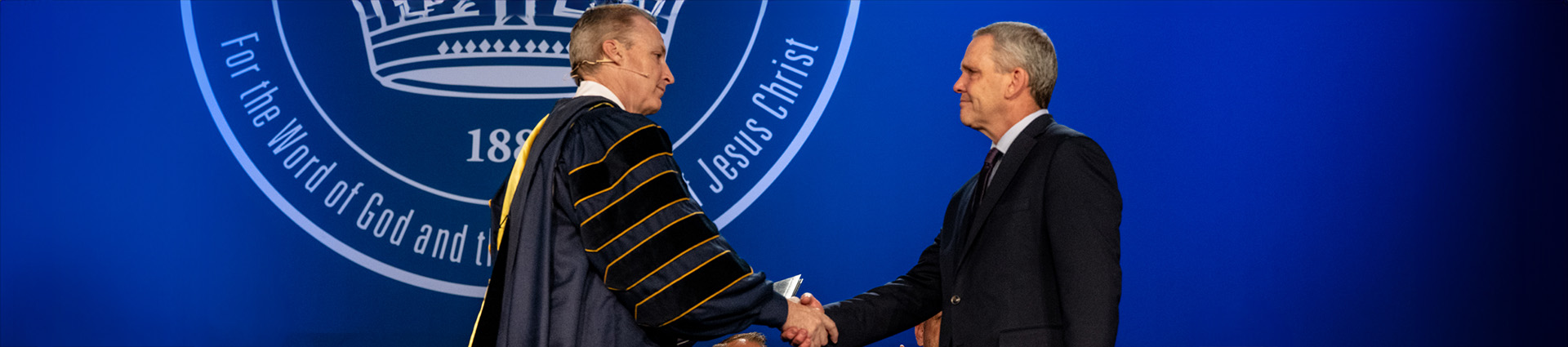 Dr. Thomas White presents Grace Maxwell's honorary degree to her father Dean at Cedarville's commencement.