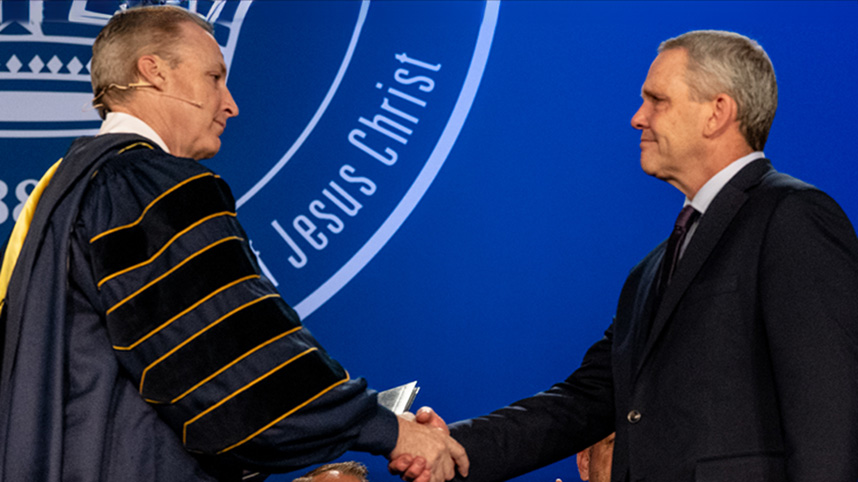 Dr. Thomas White presents Grace Maxwell's honorary degree to her father Dean at Cedarville's commencement.