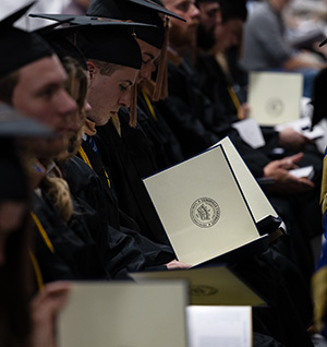 Graduates look at the degrees they received at commencement.
