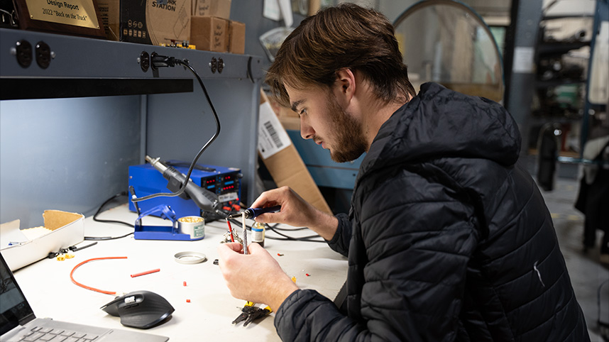 Male student working on electrical engineering project in lab.