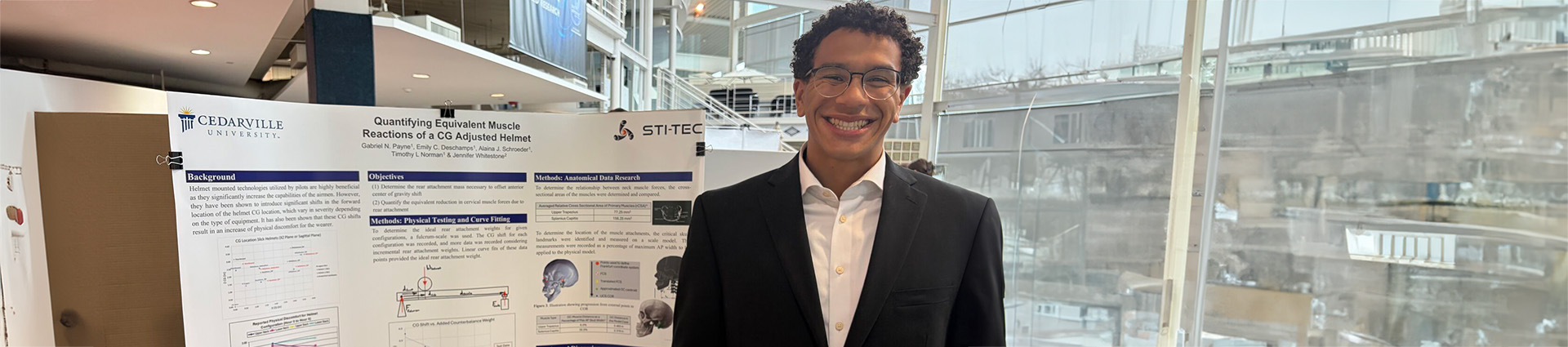 Gabriel Payne standing beside a poster display highlighting his helmet research.