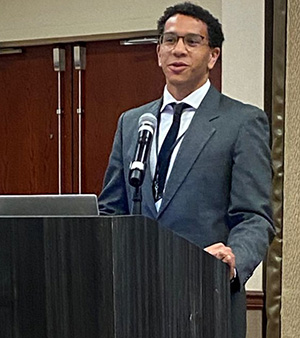 Gabriel Payne speaking at a podium.