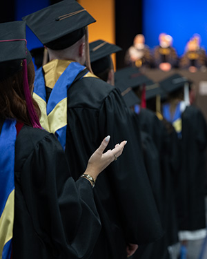 Students in caps and gowns worshiping during graduation.