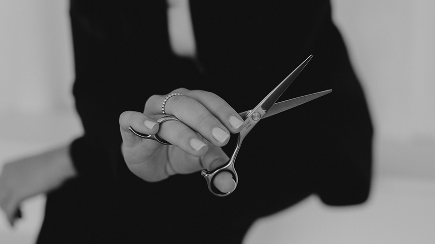 Close up image of a hand holding hair cutting shears.