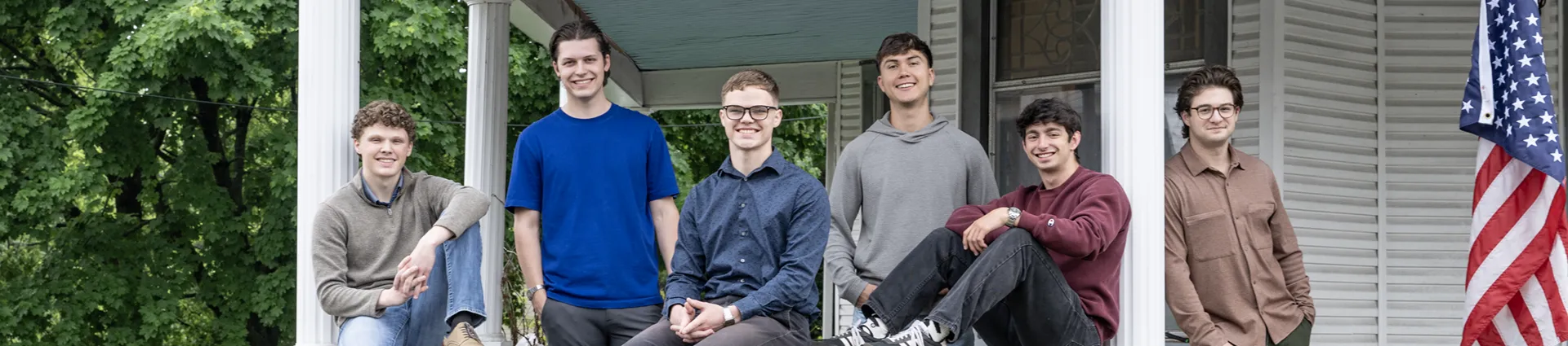 The young men who live in the Hustle House pose for a photo on the porch.