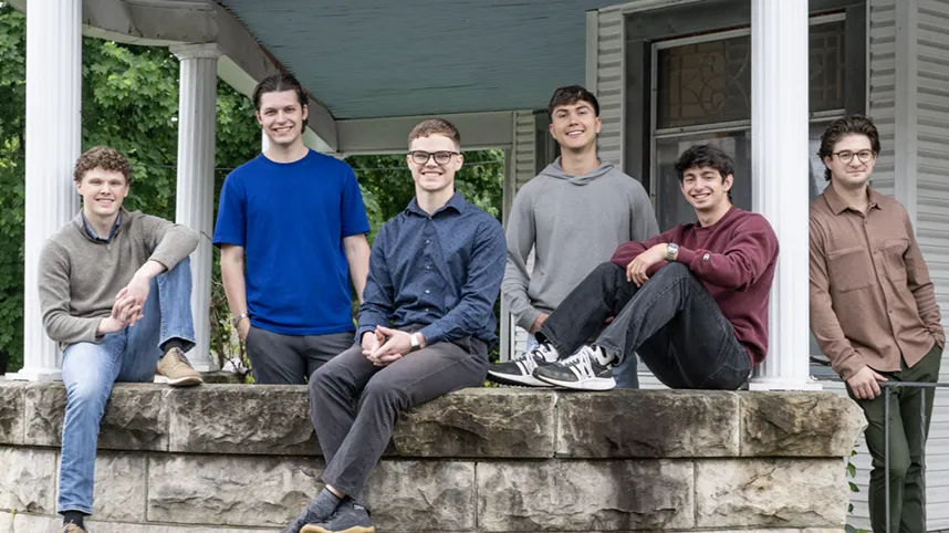The young men who live in the Hustle House pose for a photo on the porch.