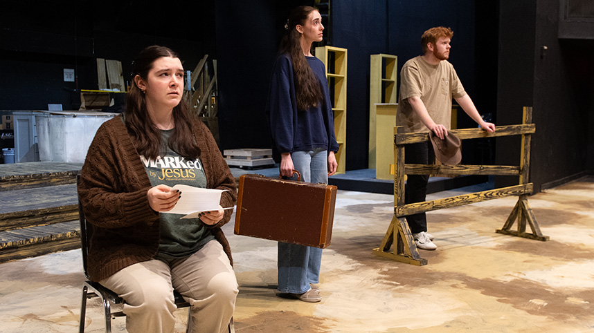 Two female and one male student rehearse on the partially finished 1930s farm set for the musical "Horizons of Gold."