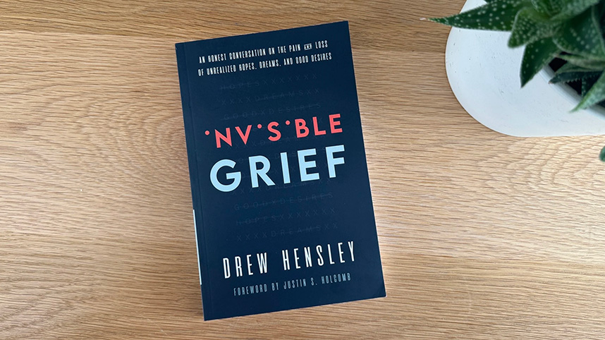 Invisible Grief book on a table beside a plant.