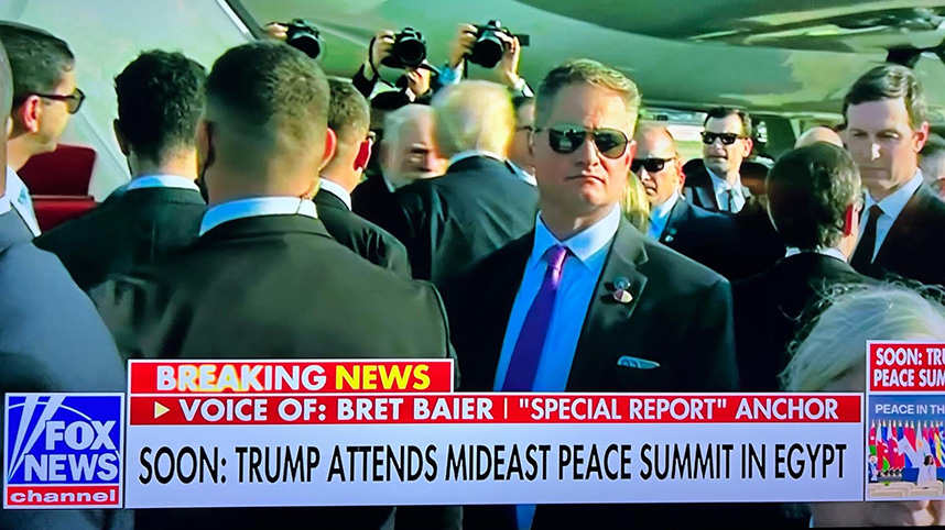 Jeff Rinehart acting in his role with the Secret Service with President Trump in the background.