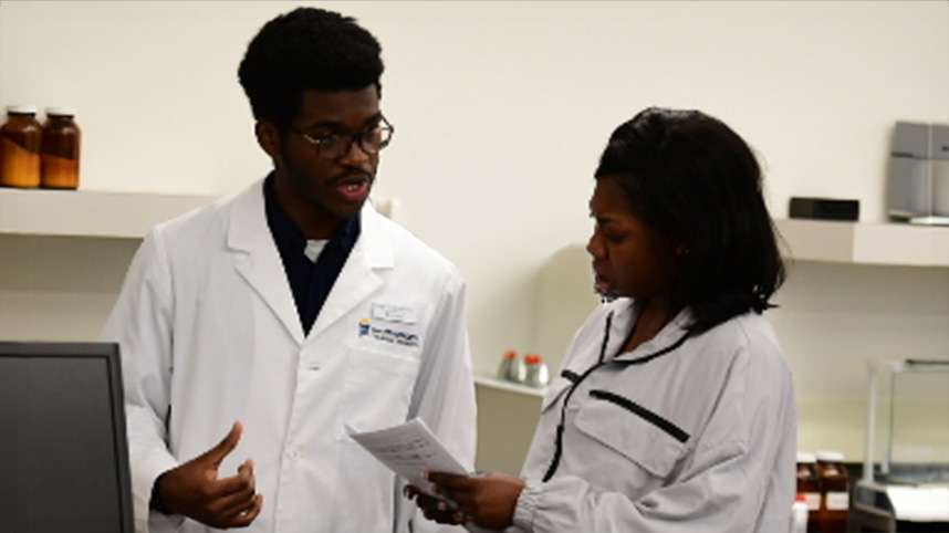 Chukwunonso Chukwuemeka speaks with Jane Addai in pharmacy lab.