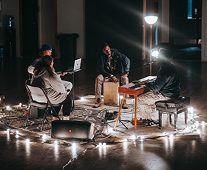 A small team of musicians play in a pool of lamplight.