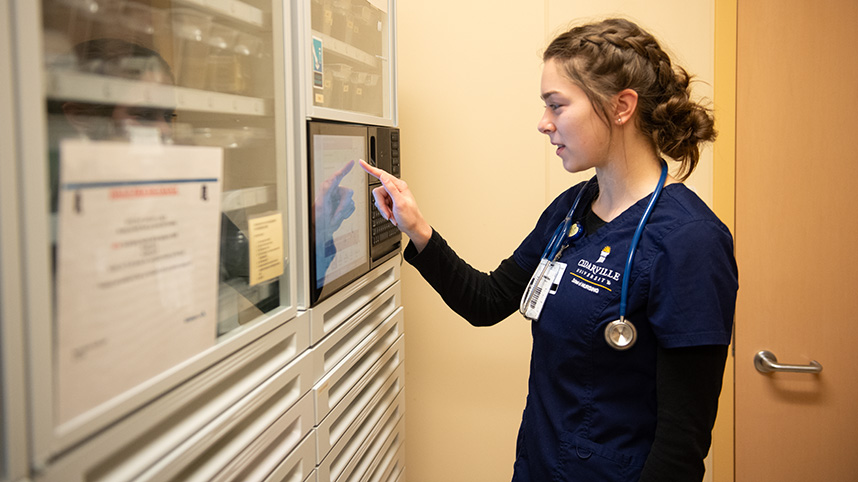 Female nursing student checking a medicine chart.