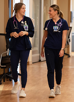 Two female nursing students walking a  hospital hallway.