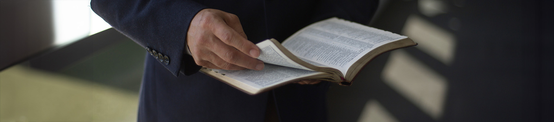 Close up of an open Bible in a man's hands.