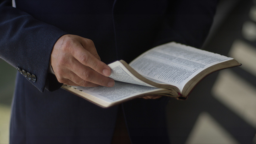 Close up of an open Bible in a man's hands.