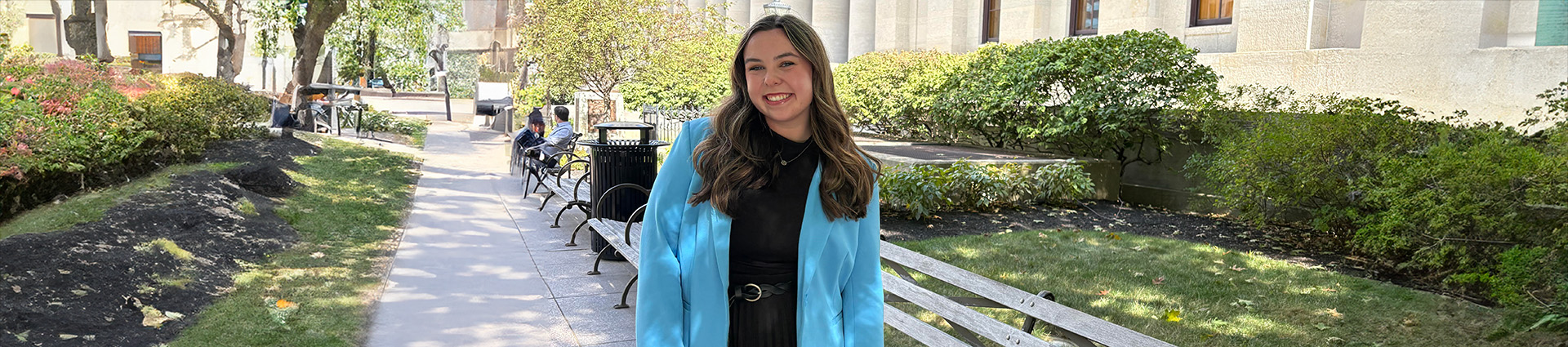 Rae Gill standing outside the Ohio Statehouse on a beautifully landscaped sidewalk.