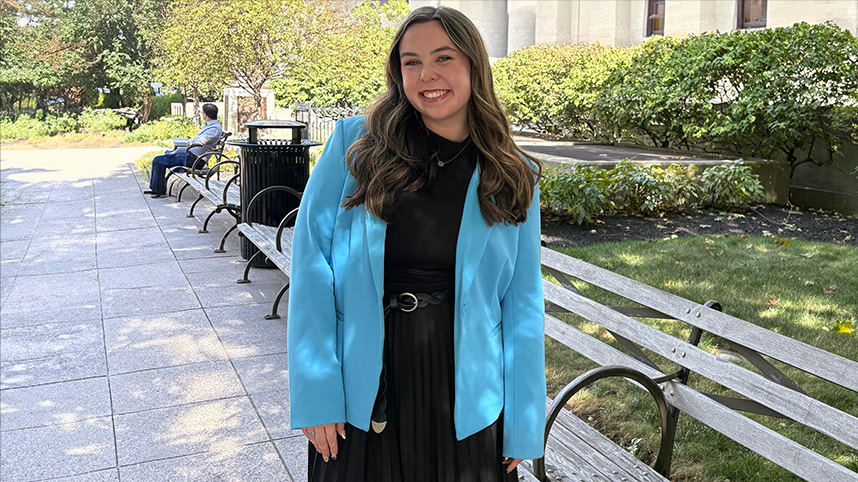 Rae Gill standing outside the Ohio Statehouse on a beautifully landscaped sidewalk.