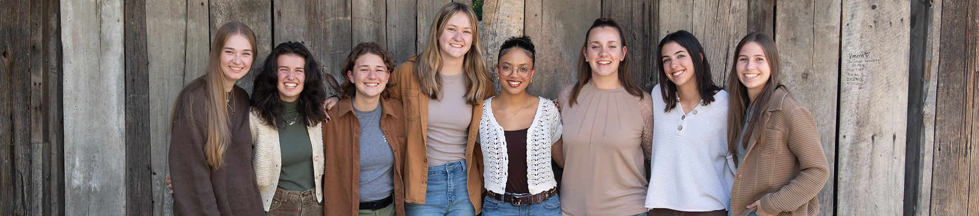 Cedarville's all female worship group, ReKindle, poses beside a barnwood wall.