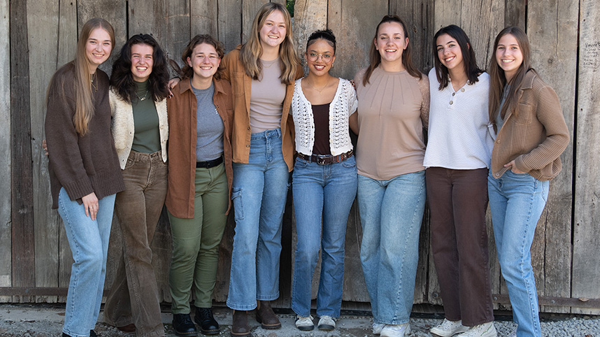 Cedarville's all female worship group, ReKindle, poses beside a barnwood wall.