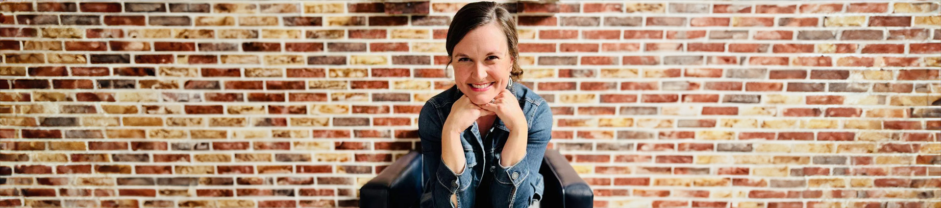 Renee Sallee sits in front of a brick wall.