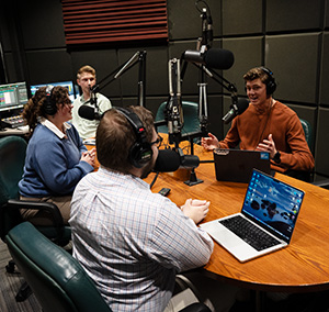 Students speaking into microphones in one of the Resound Radio studios.