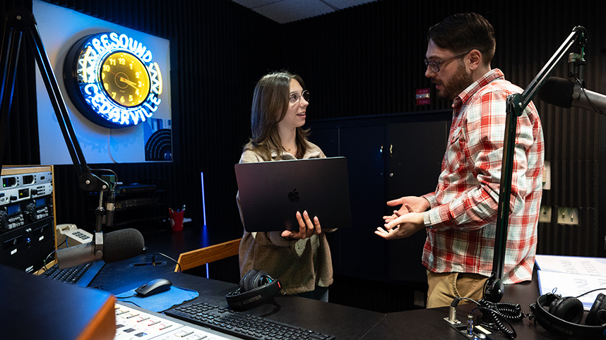 A student and professor discuss programming in the Resound Radio studio.