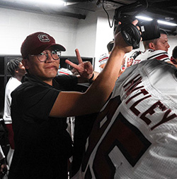 Ernest Toh filming in a football locker room.