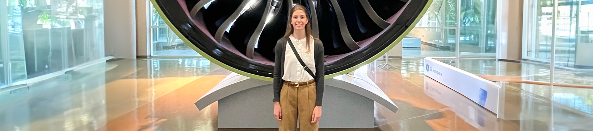 Madelyn Torrans stands in front of a jet engine and GE Aerospace.
