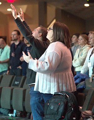 Man and woman worship with raised hands.