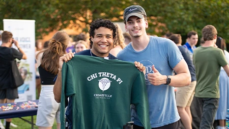 Two students holding Chi Theta Pi sweatshirt