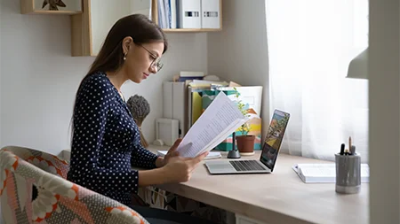 Student reviewing financial aid documents at a home workspace.