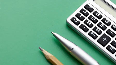 Calculator, pen, and pencil on a desk representing financial planning and budgeting.